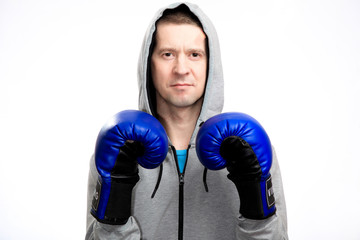 A confident calm athlete holds his hands in boxing gloves in front of him. Dressed in a sports jacket, looking at the camera. Close-up, isolated