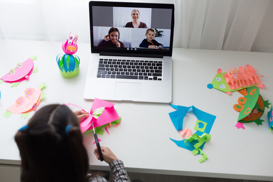 Beautiful little girl cutting paper with scissors on the art lesson class. Children education concept. Kids crafts.Back to schoo