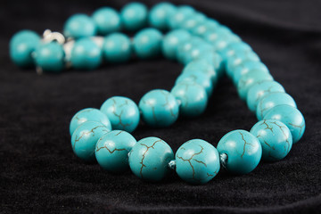 beads from turquoise semiprecious stone on black velor. close up
