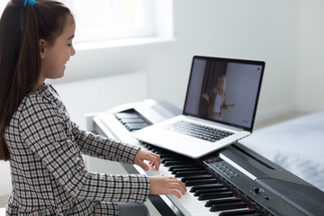 Home lesson on music for the girl on the piano. The idea of activities for the child at home during quarantine. Music concept