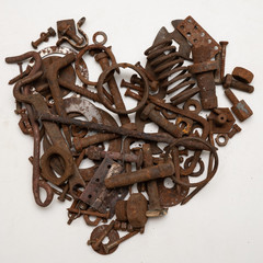 A heart shaped figure laid out from various assorted rusty metal old bolts, screws, nails, nuts. The concept of metallic artificial heart machine, robot, mechanism, Valentine's Day or love.