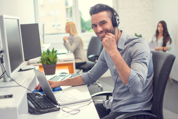 Portrait of happy smiling customer support phone operator in headset at office