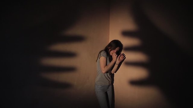 girl stands in the corner and scared in the night afraid of ghosts. nightmare concept, Palm through the frosted glass. Horror video.
