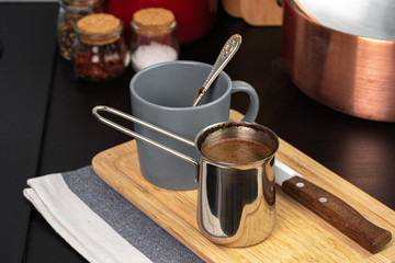 Brewed coffee in a metal turk on a kitchen counter close up