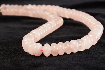 beads from rose quartz semiprecious stone on black velor. close up