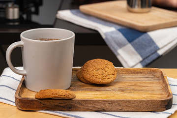 Cup of hot coffee on wooden board on kitchen table close up