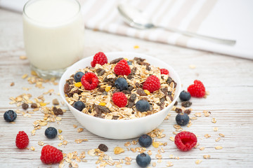 Breakfast Served in the morning with corn flakes Whole grains and raisins with milk in cups and Strawberry, Blueberry, Raspberry, Kiwi on the wood table,Diet food or healthy food in the morning.