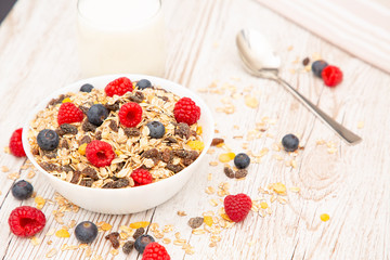 Breakfast Served in the morning with corn flakes Whole grains and raisins with milk in cups and Strawberry, Blueberry, Raspberry, Kiwi on the wood table,Diet food or healthy food in the morning.
