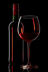 Red wine. Bottle with elegant glass on a black background.