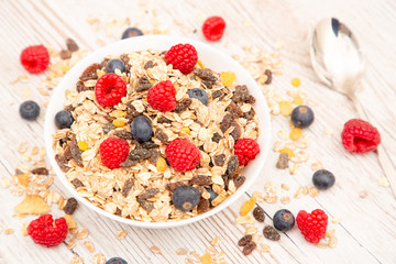Breakfast Served in the morning with corn flakes Whole grains and raisins with milk in cups and Strawberry, Blueberry, Raspberry, Kiwi on the wood table,Diet food or healthy food in the morning.