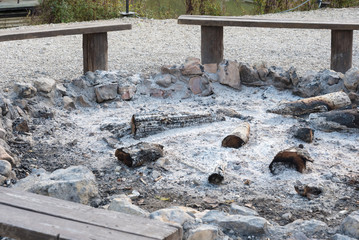 Fire pit with ashes. Clearing after a large fire. There are benches all around.