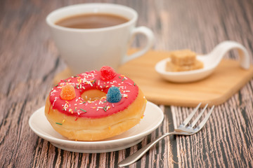 Dessert, Donuts, chocolate and strawberry circles, sugar and cream on Donuts and hot coffee cups, preparation for a break or party on the wooden table background.
