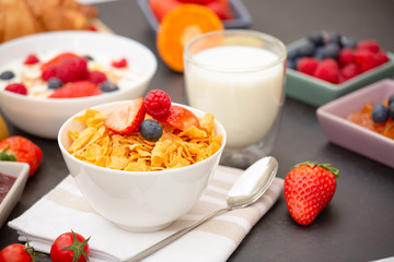Breakfast Served in the morning with Coffee, Butter croissant and corn flakes Whole grains and raisins with milk in cups and Strawberry, Raspberry, Kiwi, Fresh Orange Juice on the breakfast table.