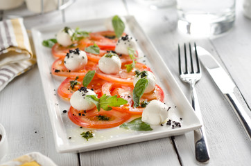 Caprese salad with tomatoes, mozzarella cheese and fresh basil leaves.