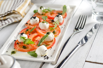 Caprese salad with tomatoes, mozzarella cheese and fresh basil leaves.