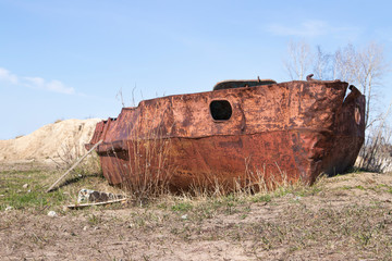 Rusty destroyed hull of an old ship on the shore.