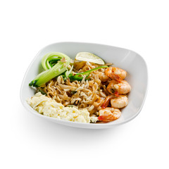 Fried udon noodles in a wok with shrimp and nuts. Served with fresh cucumber and lime. Traditional asian food.