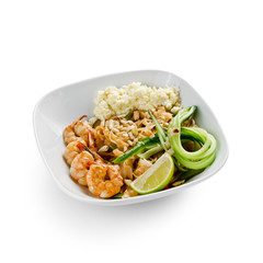 Fried udon noodles in a wok with shrimp and nuts. Served with fresh cucumber and lime. Traditional asian food.
