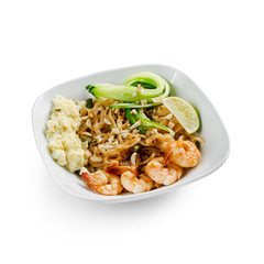 Fried udon noodles in a wok with shrimp and nuts. Served with fresh cucumber and lime. Traditional asian food.