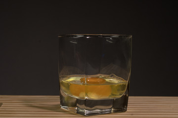 Raw egg in a glass beaker. On a black background