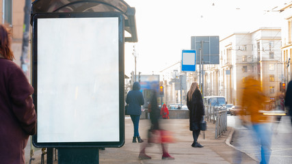Advertising billboard at the bus stop on a street full of people