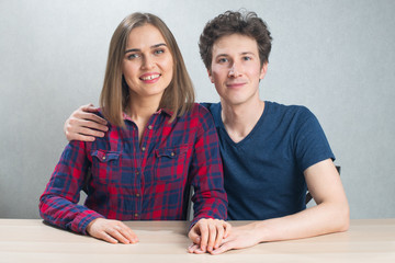 Young couple hugging sitting at the table, looking to the camera