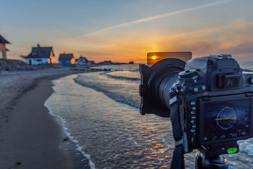 Camera DSLR on the tripod with ND filter by sunset photography at Baltic sea, taking a picture of a beautiful sunset, using a gray filter at sunset, sunrise