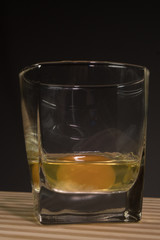 Raw egg in a glass beaker. On a black background