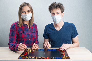Board game play, couple in medical mask, have fun staying home during quarantine