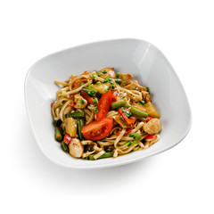 Fried udon noodles in a wok with chicken, string beans and pineapple slices. Traditional asian food.