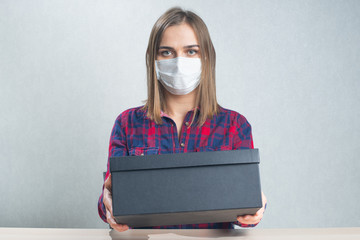 Delivery woman wearing mask, holding cardboard black premium box