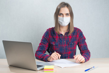 Woman working from home with laptop, wearing protection medical mask