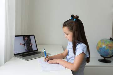 Pretty stylish schoolgirl studying homework math during her online lesson at home, social distance during quarantine, self-isolation, online education concept, home schooler