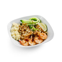 Fried udon noodles in a wok with shrimp and nuts. Served with fresh cucumber and lime. Traditional asian food. Isolated on a white background.