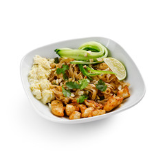 Fried udon noodles in a wok with pieces of pork. Served with tofu cheese, fresh cucumber and lime. Traditional asian food. Isolated on a white background.
