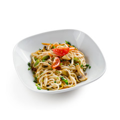 Fried udon noodles in a wok with bell pepper, Chinese cabbage and mushrooms. Traditional asian food. Isolated on a white background.