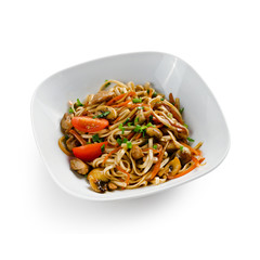 Fried udon noodles in a wok with slices of pork, carrots and mushrooms. Traditional asian food. Isolated on a white background.