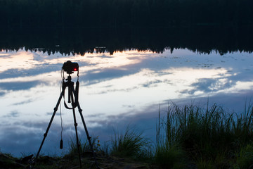 Camera on a tripod on the lake, takes a picturesque night landscape.