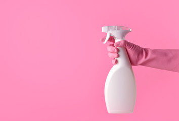 Hand with pink rubber glove holding spray bottle