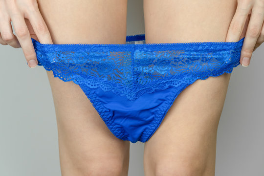 Close-up of slender legs of a young woman who takes off beautiful blue  panties Stock Photo