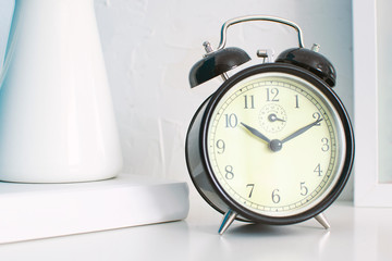Close up of alarm clock on a bedroom. White wooden bedside table and empty copy space for Editor's text.