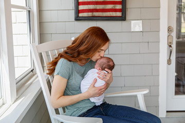 First time mom kissing her newborn baby in American home. 