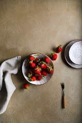 Fresh ripe delicious strawberries in a white clay bowl on a beige stone background or texture. Minimalism. Space for text.