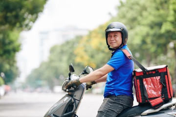 Portrait of cheerful Vietnamese man with big cooler bag working for delivery service