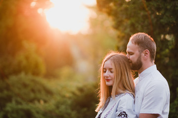 Romantic and happy caucasian couple in casual clothes hugging on the background of beautiful nature. Love, relationships, romance, happiness concept. Man and woman walking outdoors together.