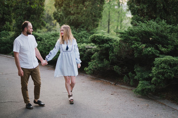 Fototapeta premium Romantic and happy caucasian couple in casual clothes hugging on the background of beautiful nature. Love, relationships, romance, happiness concept. Man and woman walking outdoors together.