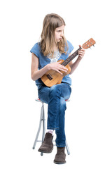 Teenage, blond girl in blue T-shirt is sitting and playing concert on ukulele instrument.