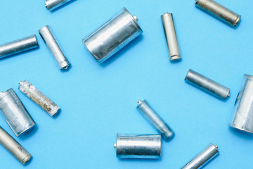 Scattered old dirty batteries aa or aaa size on blue background. Recycling concept. Save...