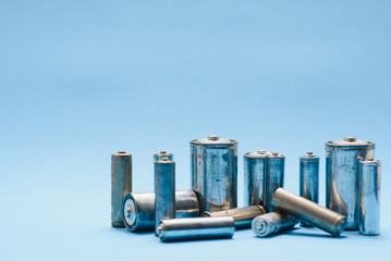 many used AA batteries on a blue background.