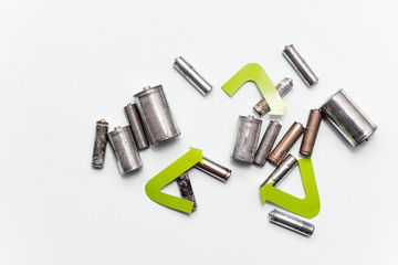 Use AA and properly dispose of batteries that are toxic to the environment and soil against a green background. The concept of technologies for processing hazardous and recyclable substances.